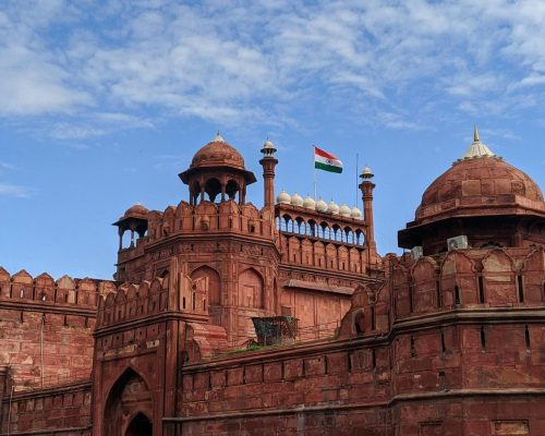 Stunning view of the historic Red Fort in Delhi, India, featuring the Indian flag against a bright blue sky.