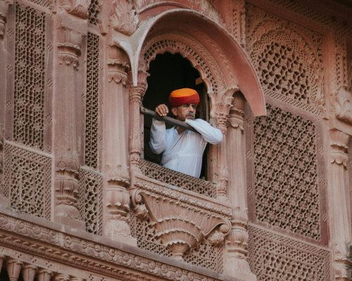 Explore the intricate details of a traditional Rajasthani facade with a man in traditional attire.